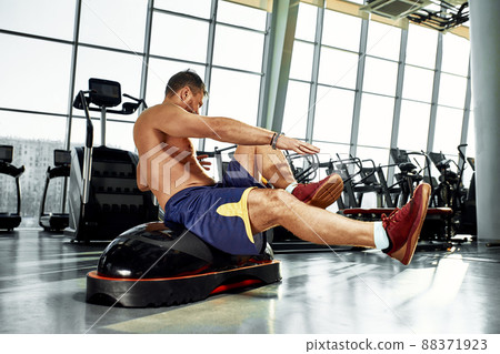 Handsome muscular men works out on functional training soft platform on a background of gym. Handsome muscular men works out on functional training soft platform on a background of gym. 88371923