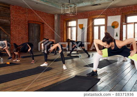 Group of diverse young people in sportswear doing stretching exercises together at the gym 88371936