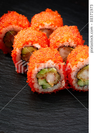 Sushi rolls california with snow crab, cream cheese, cucumber, sesame seeds and masago caviar on black background with reflection. Sushi menu, japanese kitchen. 88371973