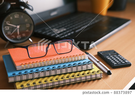 color notepads, eyeglass, clock and laptop on table color notepads, eyeglass, clock and laptop on table 88373897