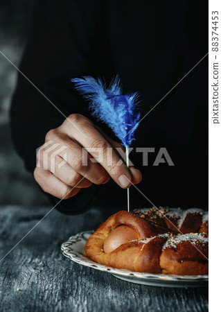 man decorates a Spanish mona de pascua cake 88374453