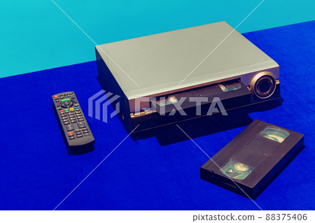 Pop art photography. Retro gadgets in modern life. Video recorder and cassette isolated on bright blue background. Vintage, retro fashion style. Concept of nostalgia Pop art photography. Retro gadgets in modern life. Video recorder and cassette isolated on bright blue background. Vintage, retro fashion style. Concept of nostalgia 88375406