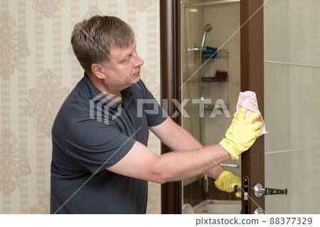 An adult blond man washes the bathroom door 88377329