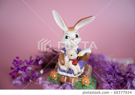 Mrs. Rabbit feeds little sheep. Porcelain figurine decorated for spring greetings, postcards, Easter greetings. 88377934