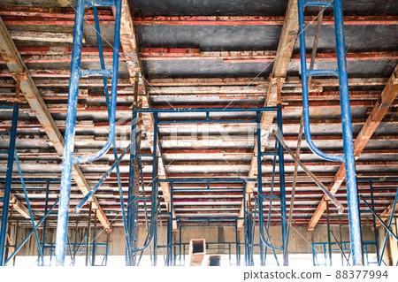 Setting up steel scaffolding to support floors for concrete work on tall buildings. A view up under the floor to support the concrete floor. Setting up a concrete pouring form on the second floor. Setting up steel scaffolding to support floors for concrete work on tall buildings. A view up under the floor to support the concrete floor. Setting up a concrete pouring form on the second floor. 88377994