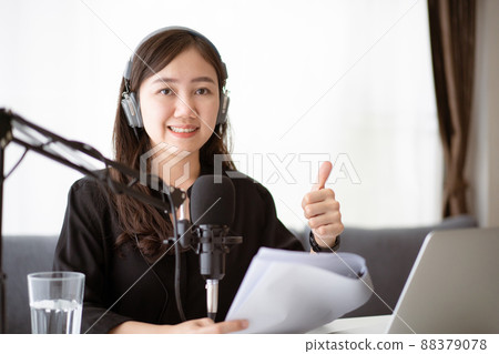 Beautiful and good looking young Asian woman arranging home podcast channel. Businesswoman recording her podcast for her online podcast live on the laptop computer and tablet. Modern working lifestyle 88379078