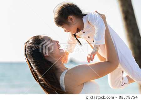 Happy asian mom holding her daughter playing together on the beach with fresh air.happy outdoor little girl hugging mother smile and love having fun enjoy with sunset on the beach.Mother day concept Happy asian mom holding her daughter playing together on the beach with fresh air.happy outdoor little girl hugging mother smile and love having fun enjoy with sunset on the beach.Mother day concept 88379754