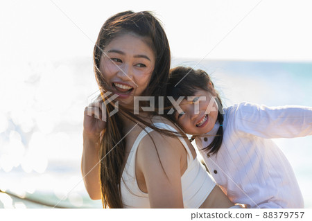 Happy asian mom holding her daughter playing together on the beach with fresh air.happy outdoor little girl hugging mother smile and love having fun enjoy with sunset on the beach.Mother day concept 88379757