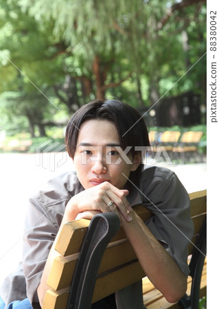 A straight-faced young man relaxing in the park A straight-faced young man relaxing in the park 88380042