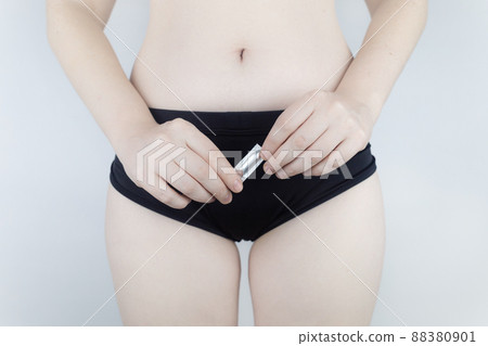 Vaginal or rectal candle in the hands of a woman against the background of the abdomen and underwear. Treatment vaginal infections, candidiasis, thrush and sexually transmitted infections 88380901