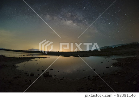 The stars in the sky reflect the light at night. The Milky Way above the mountains and the pond Mae Prachan Dam and Reservoir, Phetchaburi, Thailand 88381146