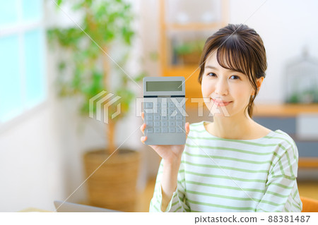 Young housewife with a calculator in the room 88381487