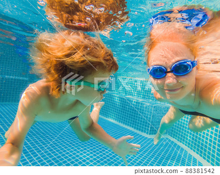 Little boy learning to swim in a swimming pool, mother holding the child Little boy learning to swim in a swimming pool, mother holding the child 88381542