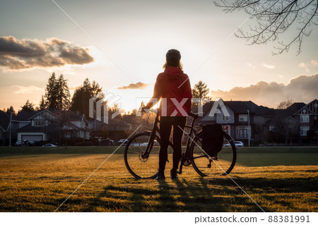 Adventurous Woman Standing with a bicycle at a Park in Modery City Suburbs. Adventurous Woman Standing with a bicycle at a Park in Modery City Suburbs. 88381991