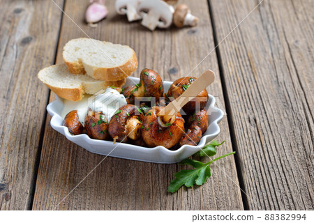 Fried mushrooms with shallots and parsley, served with a garlic dip sauce in a reusable food tray 88382994