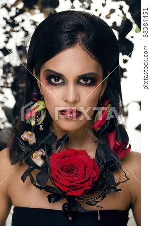 pretty brunette woman with rose jewelry, black and red, bright make up like a vampire closeup red lips 88384451