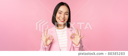 Okay, excellent. Businesswoman in corporate suit, showing ok, approval gesture, recommending smth, give positive feedback and smiling pleased, posing over pink background Okay, excellent. Businesswoman in corporate suit, showing ok, approval gesture, recommending smth, give positive feedback and smiling pleased, posing over pink background 88385283