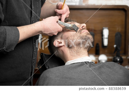 Professional barber cutting beard of handsome man 88388639