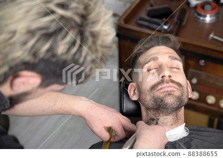 Professional barber cutting beard of handsome man 88388655