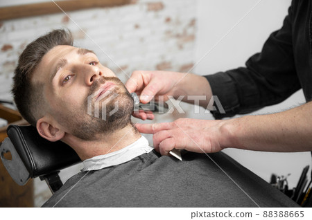 Professional barber cutting beard of handsome man 88388665