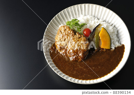 A bird's-eye view of a coarse hamburger curry with stewed vegetables and parsley on a black background 88390134