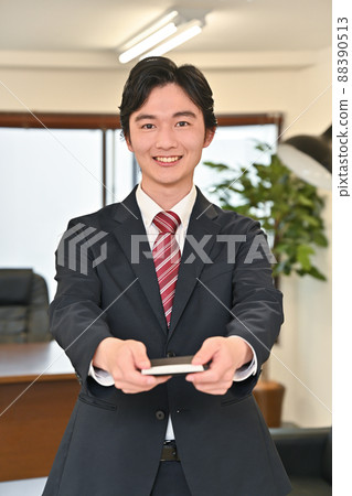 A man presenting a business card with a smile 88390513