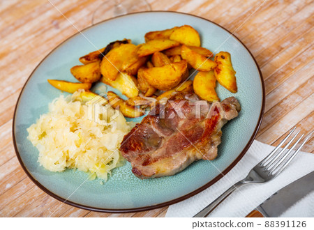 Roasted pork steak with baked potatoes and pickled cabbage Roasted pork steak with baked potatoes and pickled cabbage 88391126