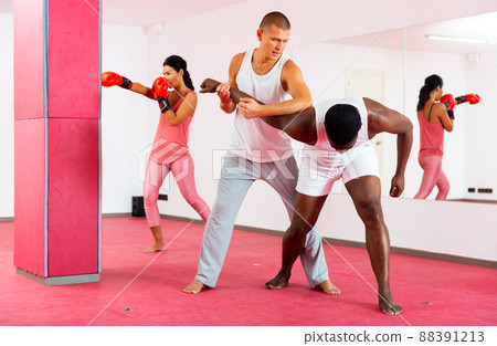 Men and woman exercising self-protection martial arts in gym 88391213