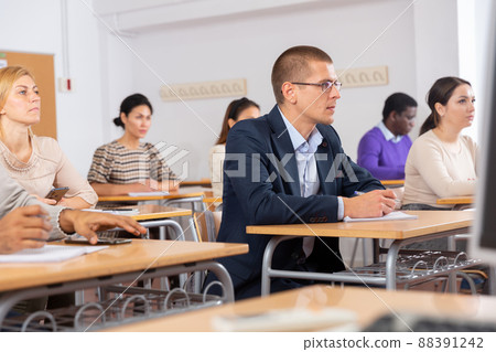 Intelligent adult man in glasses listening to lecture in classroom 88391242