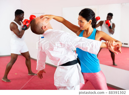 Woman exercising with trainer and man boxing in gym 88391302