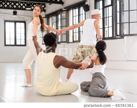 Group of young people dancers holding hands standing in circle Group of young people dancers holding hands standing in circle 88391361