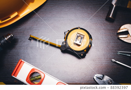 Measuring tape on wooden table background with mechanic tools alongside 88392397