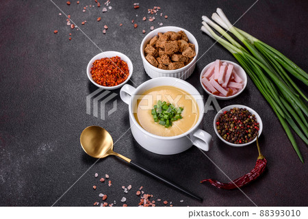 Cream soup with potatoes, leek and peas on a dark concrete table Cream soup with potatoes, leek and peas on a dark concrete table 88393010
