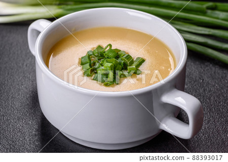Cream soup with potatoes, leek and peas on a dark concrete table 88393017
