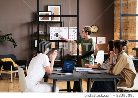 Young woman with prosthetic arm presenting her report to colleagues at table during meeting at office Young woman with prosthetic arm presenting her report to colleagues at table during meeting at office 88393093