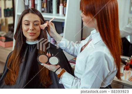 Professional makeup artist applying bronzer powder with a brush in beauty salon 88393923