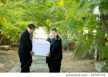 Bereaved family carrying a casket at a funeral 88395356