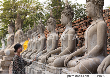 Asian girl exploring the row of Buddha statues at Wat Yai Chai Mongkhon temple in Ayutthaya, Thailand 88398922