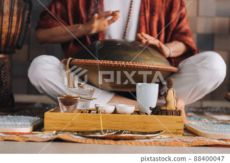Close-up of a man's hand playing a modern musical instrument - the Orion tongue drum during the tea ceremony 88400047