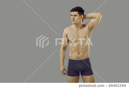 Handsome young male model posing topless in underwear isolated on gray background 88402269
