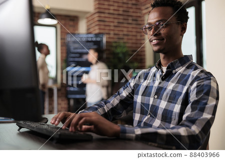 Smiling confident african american software engineer developing machine learning algorithm in order to sustain system security stability. Cyber developer creating network using binary encryption. 88403966