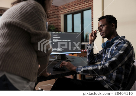 Software developers sitting at desk and developing a functional data encryption system. Multiethnic cyber security team members in agency office writing cloud database processing algorithm. 88404110