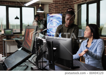 3D graphic diverse artists in office workspace conversating about design of project. Development department team leader helping coworker with software issue while working on digital art. 88404120