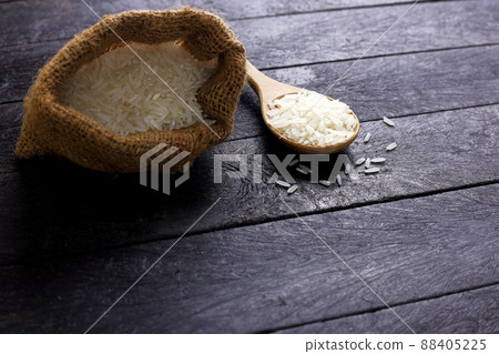 Spoon of uncooked rice and sag of rice grain on black background wih soft light Spoon of uncooked rice and sag of rice grain on black background wih soft light 88405225