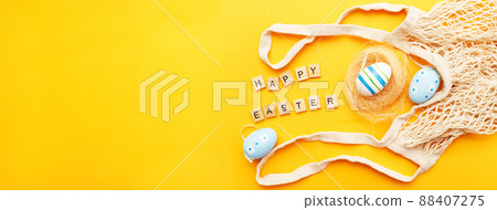 inscription happy easter with colorful painted eggs and cotton string bag on orange background 88407275