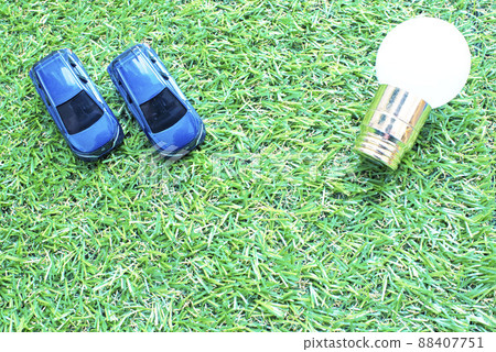 Two electric cars and miniature bulbs on the lawn 88407751