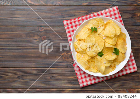 Potato chips on bowl with napkin on colored background. Delicious crispy potato chips in bowl. Space for text. Top view Potato chips on bowl with napkin on colored background. Delicious crispy potato chips in bowl. Space for text. Top view 88408244