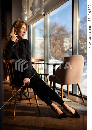Beautiful girl in a black jacket in a cafe, posing on the camera. 88410862