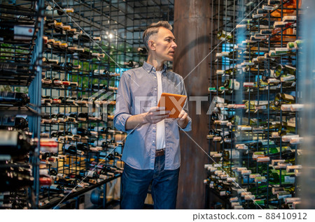 A wine store owner making a revision and looking involved A wine store owner making a revision and looking involved 88410912