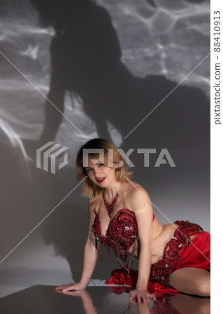 Beautiful girl with long black hair in a red oriental dress dancing belly dance in the studio room. Arab culture. Beautiful girl with long black hair in a red oriental dress dancing belly dance in the studio room. Arab culture. 88410913